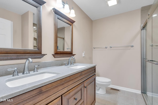 bathroom featuring tile patterned flooring, vanity, a shower with shower door, and toilet