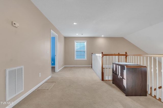 hallway with lofted ceiling and light colored carpet