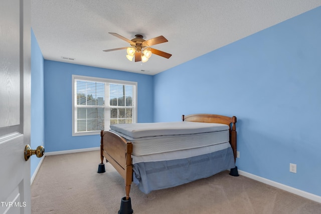 bedroom featuring light colored carpet, a textured ceiling, and ceiling fan