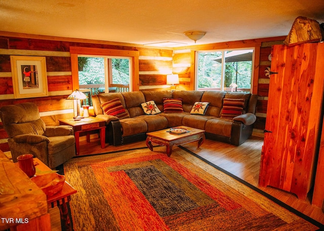 living room with hardwood / wood-style floors, log walls, and a wealth of natural light