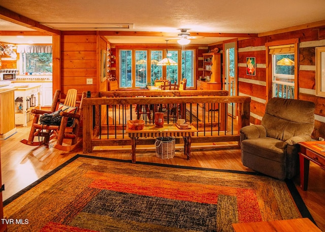 living room with ceiling fan, hardwood / wood-style floors, a textured ceiling, and wood walls