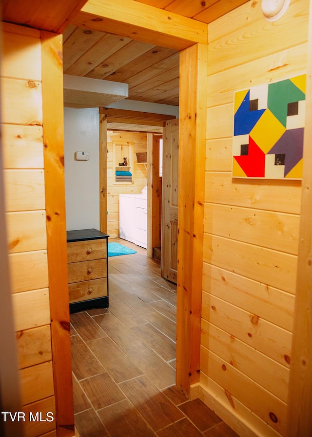 hallway featuring washing machine and dryer and wood walls