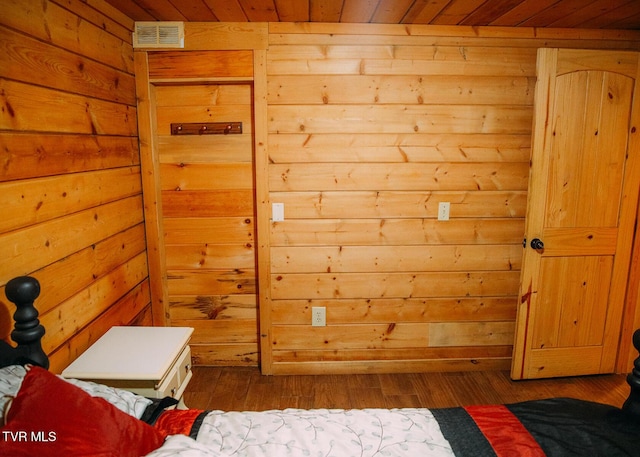 bedroom with wood ceiling, dark wood-type flooring, and wooden walls