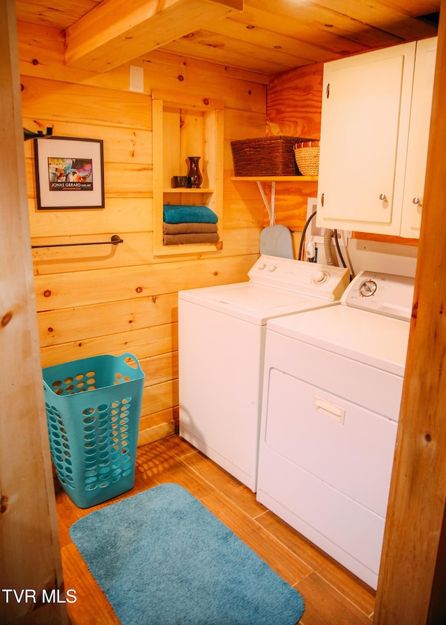 clothes washing area featuring cabinets, separate washer and dryer, wooden ceiling, and wooden walls