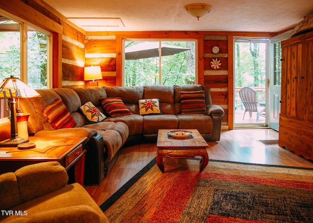 living room with hardwood / wood-style flooring, log walls, and a textured ceiling