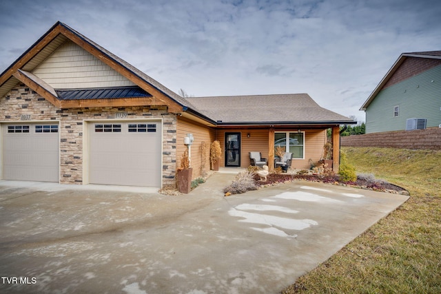 view of front of house featuring a porch, a standing seam roof, driveway, and a garage