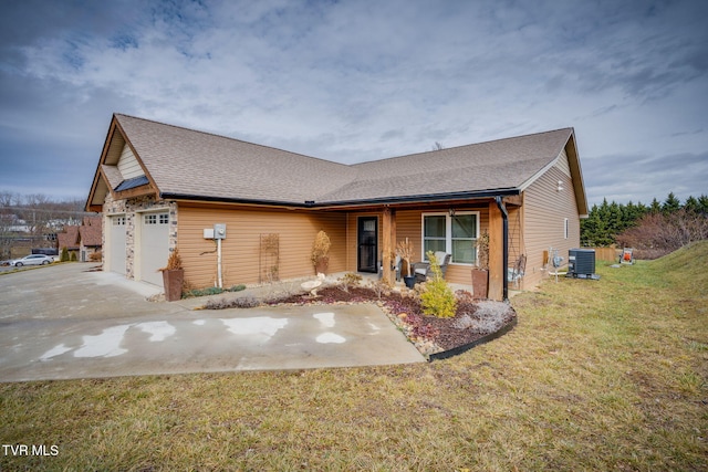 view of front of home with driveway, roof with shingles, an attached garage, central AC, and a front yard