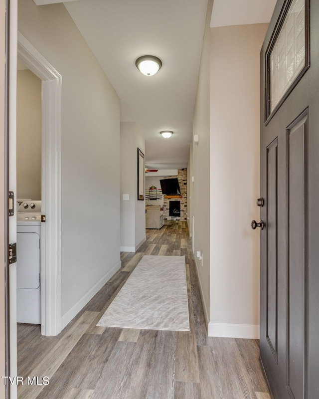 foyer featuring washer / clothes dryer, a fireplace, wood finished floors, and baseboards