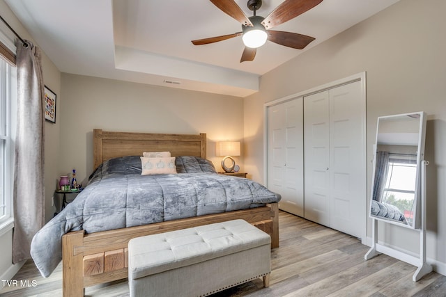 bedroom featuring visible vents, baseboards, a ceiling fan, light wood-style floors, and a closet