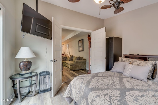 bedroom with ceiling fan, light wood-style flooring, and baseboards