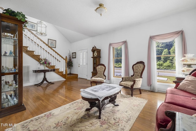 living room with plenty of natural light, hardwood / wood-style floors, lofted ceiling, and a textured ceiling