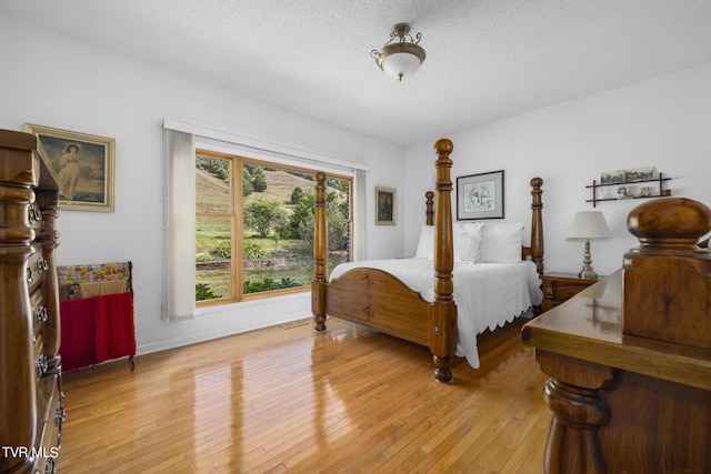 bedroom featuring light hardwood / wood-style floors and a textured ceiling