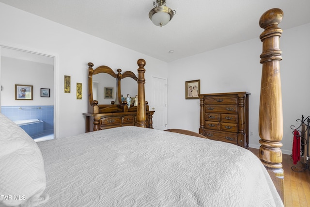 bedroom featuring connected bathroom and hardwood / wood-style flooring