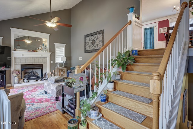 stairs with hardwood / wood-style flooring, ceiling fan, a fireplace, and high vaulted ceiling