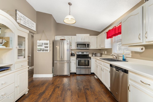 kitchen with lofted ceiling, sink, appliances with stainless steel finishes, white cabinets, and decorative light fixtures