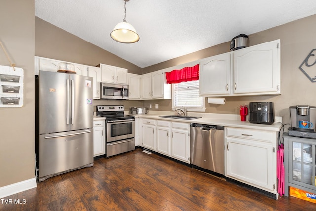 kitchen with lofted ceiling, sink, decorative light fixtures, stainless steel appliances, and white cabinets