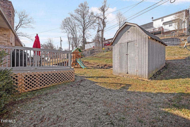 view of yard featuring a storage unit, a playground, and a deck