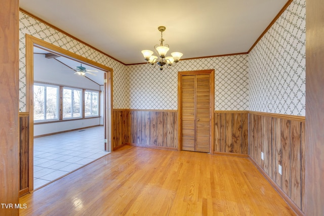 unfurnished dining area featuring ceiling fan with notable chandelier, ornamental molding, and light hardwood / wood-style floors