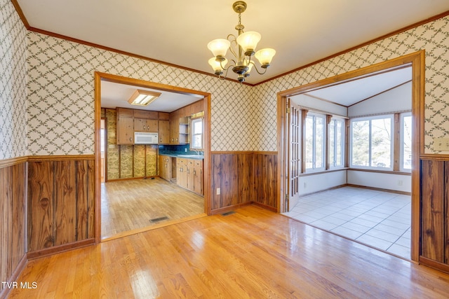 kitchen featuring sink, an inviting chandelier, decorative light fixtures, light wood-type flooring, and ornamental molding