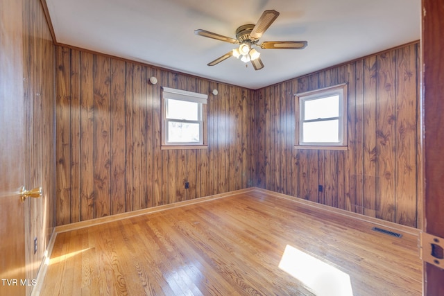 empty room with a healthy amount of sunlight, ceiling fan, and light hardwood / wood-style flooring