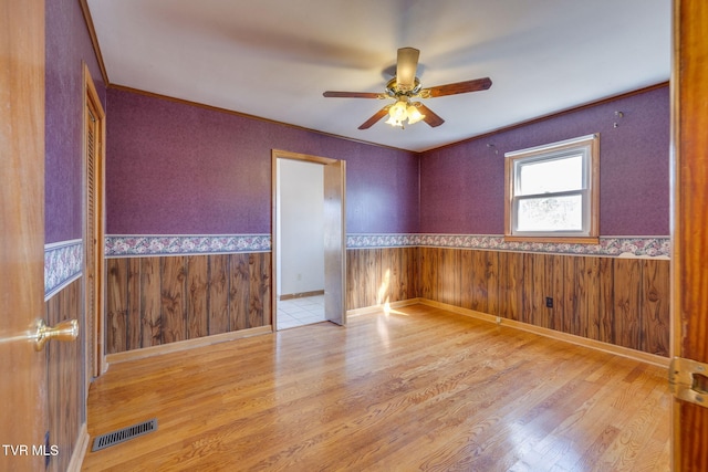 empty room with crown molding and light wood-type flooring