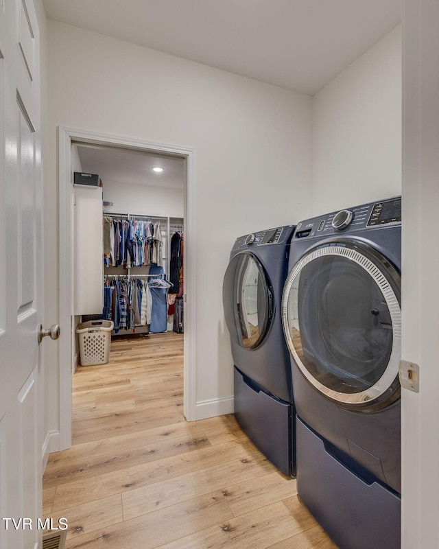 washroom with separate washer and dryer and light hardwood / wood-style flooring