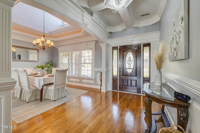 entrance foyer featuring an inviting chandelier, crown molding, decorative columns, and hardwood / wood-style flooring