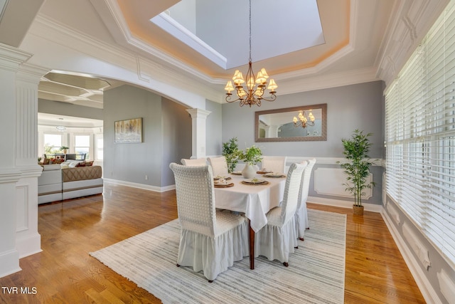 dining area with ornamental molding, decorative columns, and light wood-type flooring