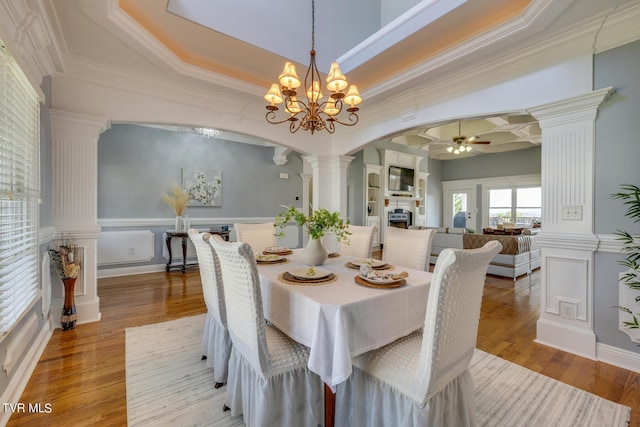 dining space featuring crown molding, decorative columns, and light wood-type flooring