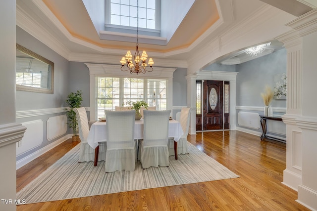 dining room with a healthy amount of sunlight, a chandelier, decorative columns, and light wood-type flooring