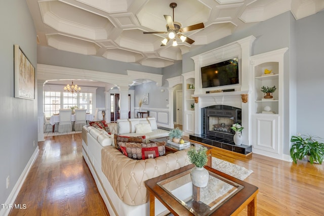 living room featuring coffered ceiling, wood-type flooring, built in features, ceiling fan, and a tiled fireplace