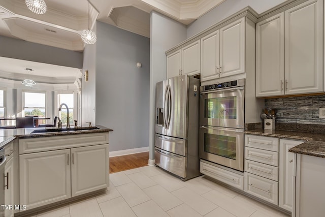 kitchen with decorative light fixtures, sink, backsplash, dark stone counters, and stainless steel appliances