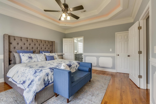 bedroom with ceiling fan, wood-type flooring, a tray ceiling, and ornamental molding