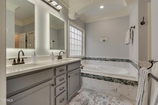 bathroom with vanity, a relaxing tiled tub, and ornamental molding