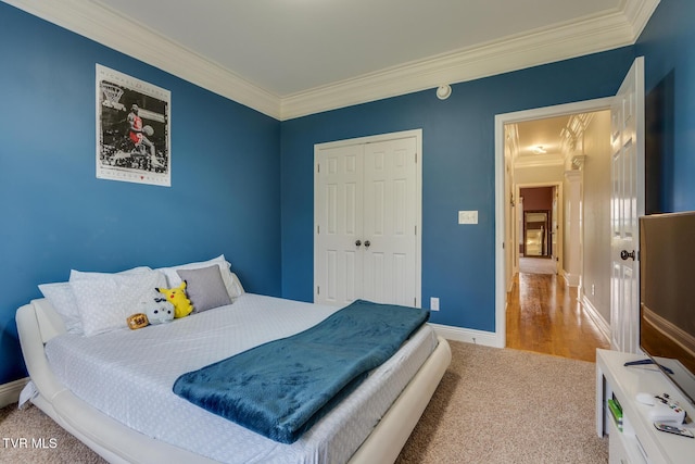 carpeted bedroom with ornamental molding and a closet