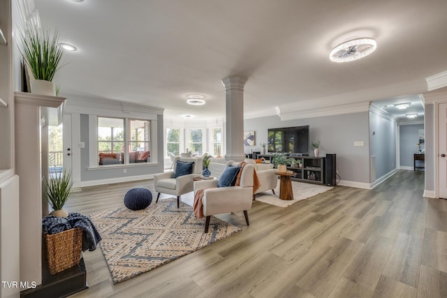 living room with decorative columns, crown molding, and hardwood / wood-style floors