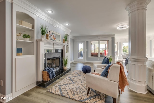 living room with crown molding, wood-type flooring, and decorative columns