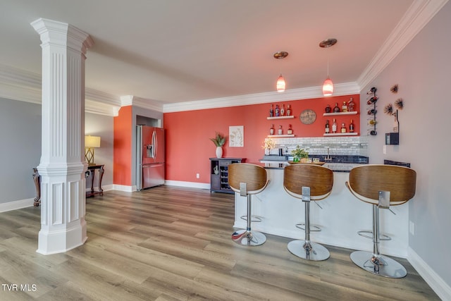 bar featuring decorative columns, stainless steel refrigerator with ice dispenser, wood-type flooring, and crown molding