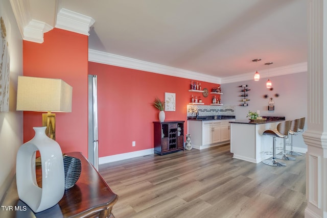 kitchen with a breakfast bar, white cabinetry, crown molding, decorative light fixtures, and light hardwood / wood-style flooring