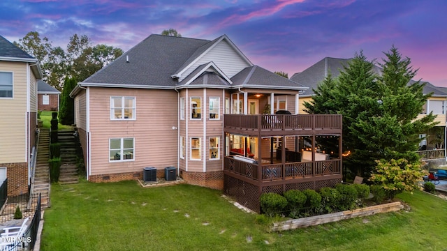 back house at dusk with central AC unit, a deck, and a lawn