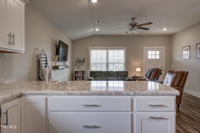 kitchen featuring lofted ceiling, white cabinetry, dark hardwood / wood-style flooring, ceiling fan, and light stone countertops