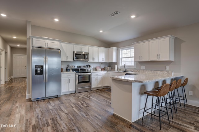 kitchen with lofted ceiling, sink, appliances with stainless steel finishes, white cabinets, and dark hardwood / wood-style flooring