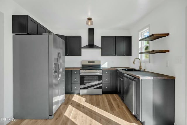 kitchen with sink, gray cabinetry, stainless steel appliances, wall chimney exhaust hood, and light wood-type flooring