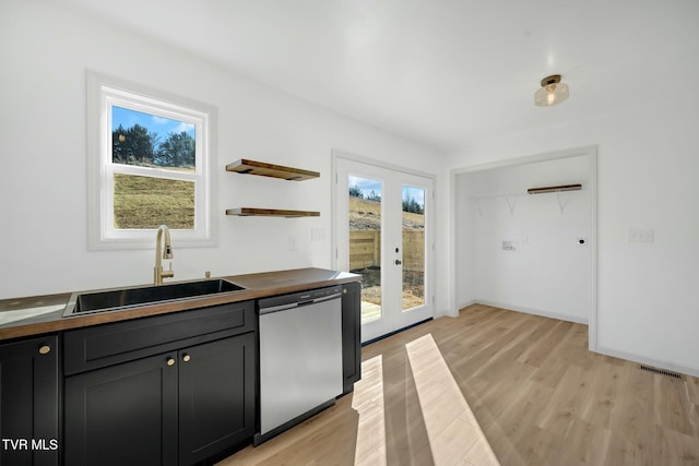 kitchen featuring sink, butcher block counters, stainless steel dishwasher, light wood-type flooring, and french doors