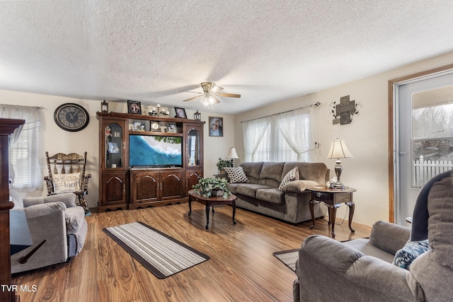 living room with hardwood / wood-style flooring, a textured ceiling, and ceiling fan