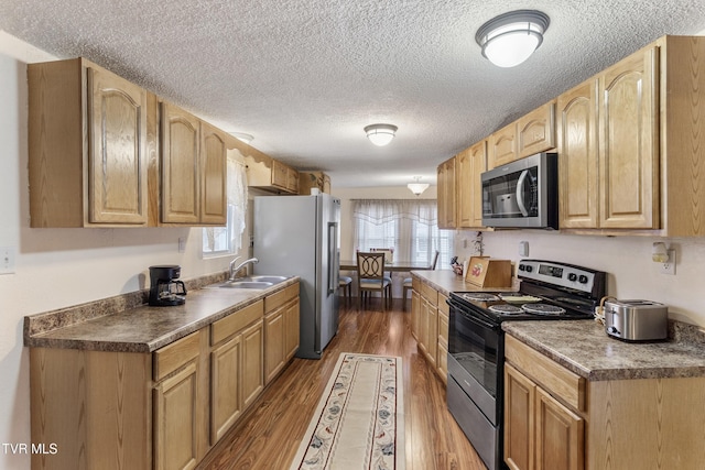 kitchen with stainless steel appliances, wood-type flooring, sink, and a textured ceiling