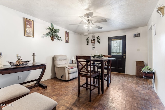 dining room with ceiling fan, a textured ceiling, and dark parquet floors