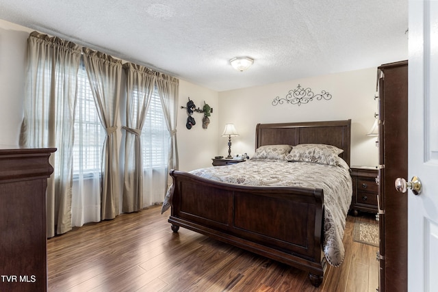 bedroom featuring a textured ceiling and dark hardwood / wood-style flooring