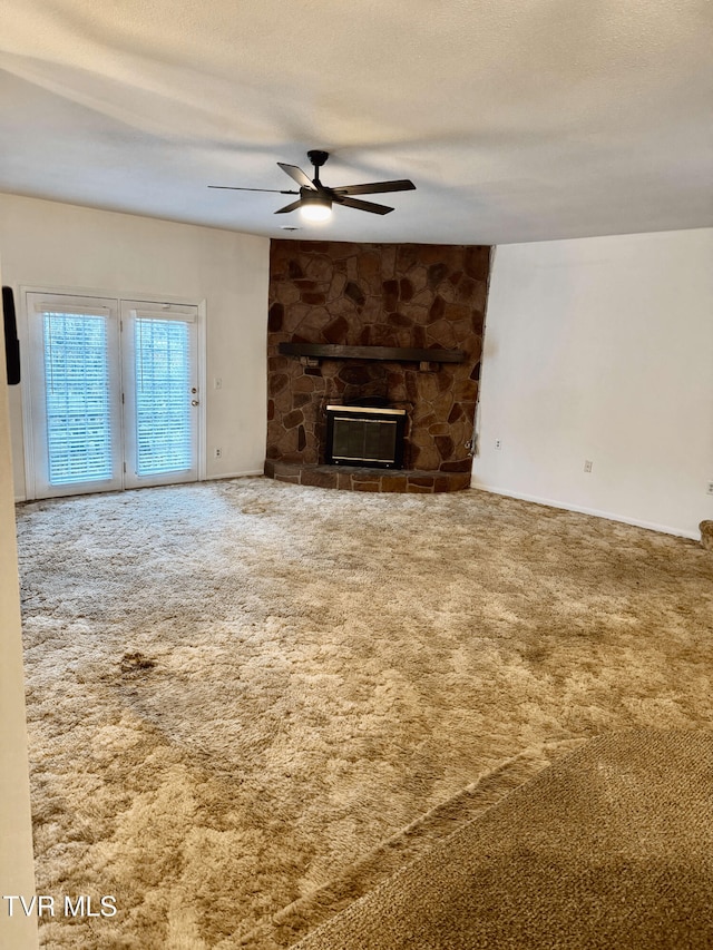 unfurnished living room featuring ceiling fan, a fireplace, carpet flooring, and a textured ceiling