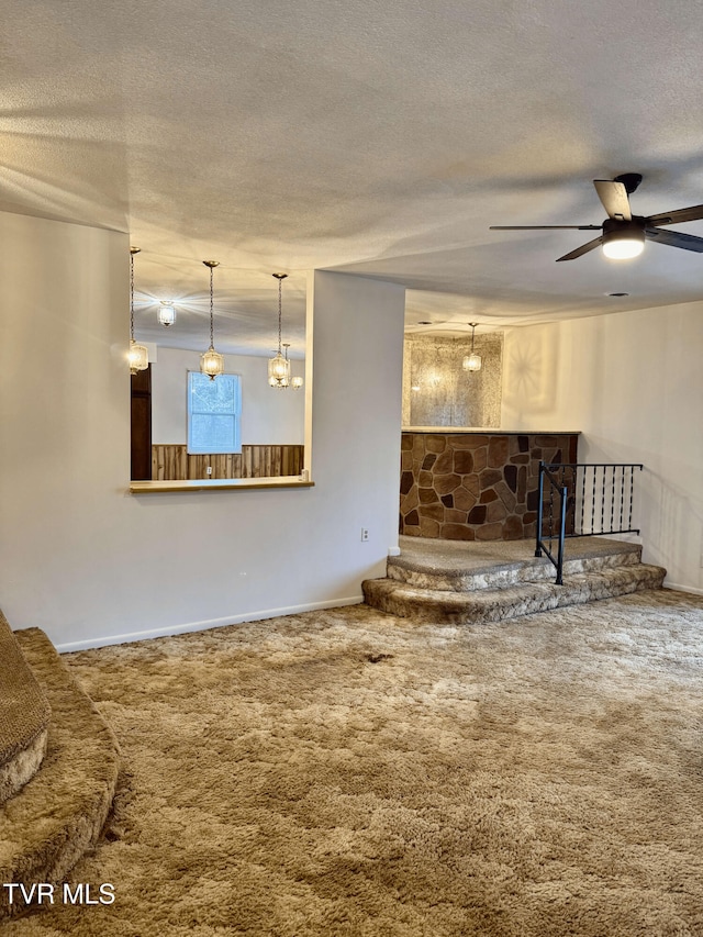 unfurnished living room featuring ceiling fan, carpet, and a textured ceiling